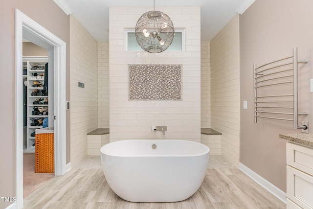 full bath featuring a freestanding bath, radiator, vanity, a walk in shower, and baseboards