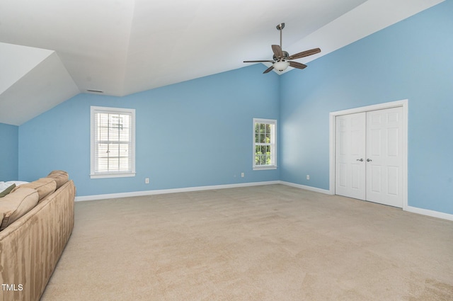 unfurnished bedroom featuring vaulted ceiling, light colored carpet, baseboards, a closet, and ceiling fan