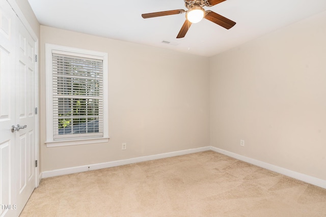 unfurnished room featuring light colored carpet, baseboards, and a ceiling fan