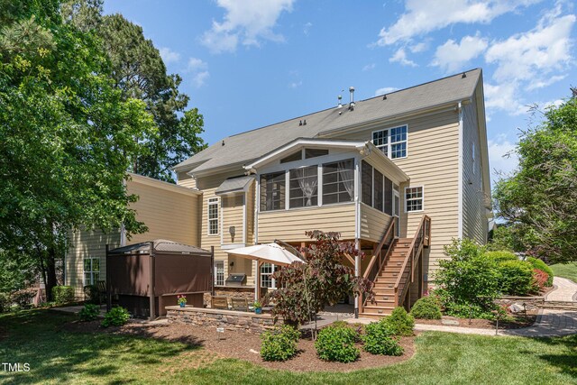back of property featuring a sunroom, stairway, and a lawn
