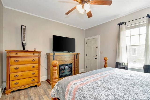 201 W 16th St, Lumberton, NC 28358 - bedroom with light wood finished floors, crown molding, baseboards, ceiling fan, and a glass covered fireplace