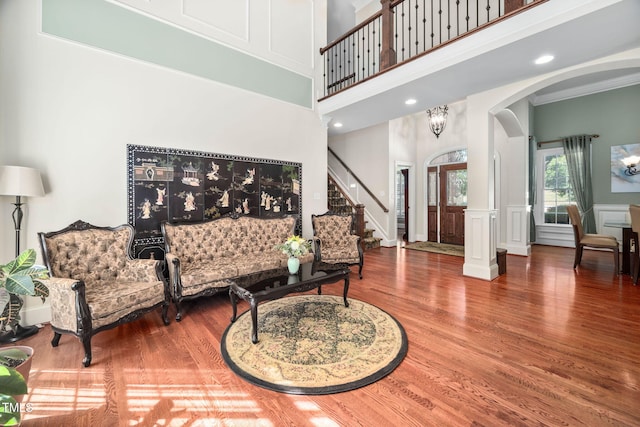 39 Forked Pine Ct, Chapel Hill, NC 27517 - living room featuring arched walkways, wood finished floors, a towering ceiling, stairs, and a decorative wall