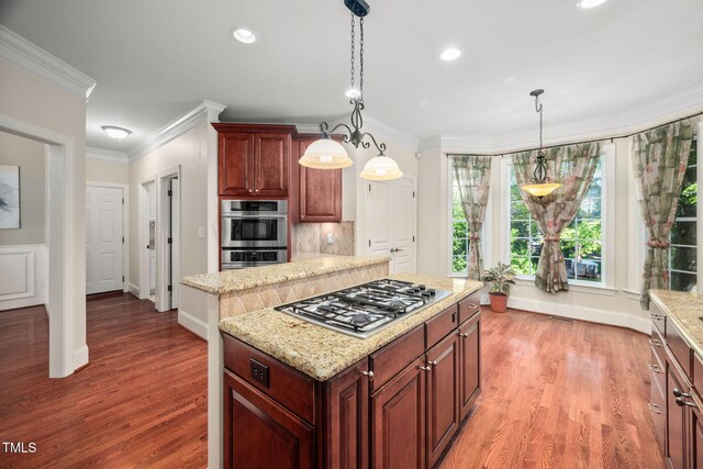39 Forked Pine Ct, Chapel Hill, NC 27517 - kitchen with appliances with stainless steel finishes, ornamental molding, a kitchen island, light wood finished floors, and decorative light fixtures