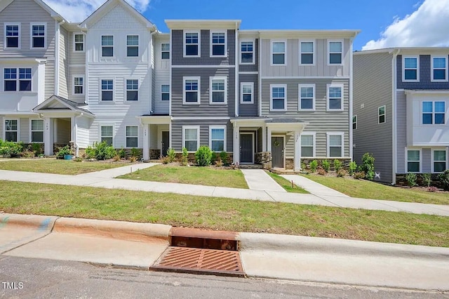townhome / multi-family property featuring stone siding and a front yard