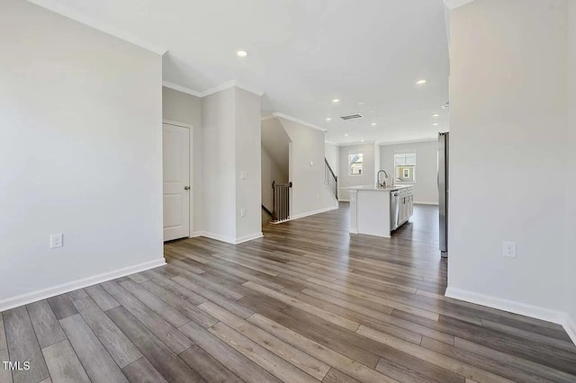 unfurnished living room with recessed lighting, dark wood-style floors, a sink, crown molding, and baseboards