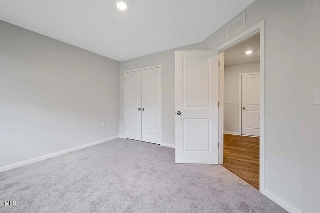 unfurnished bedroom featuring carpet floors, baseboards, recessed lighting, and a closet