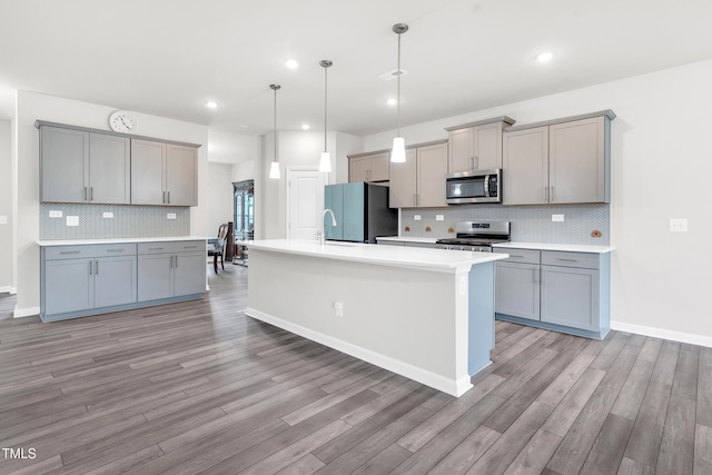 4601 Okeechobee Ct, Fuquay Varina, NC 27526 - kitchen featuring stainless steel appliances, gray cabinetry, light wood-style floors, and recessed lighting
