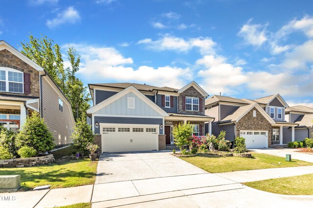 craftsman house featuring board and batten siding, concrete driveway, a front yard, an attached garage, and brick siding