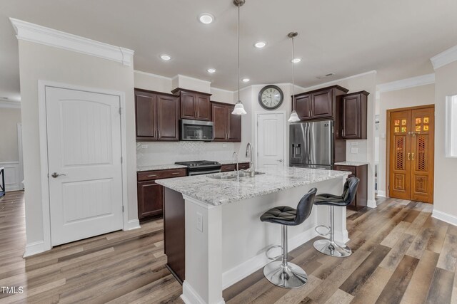 kitchen with stainless steel appliances, a sink, light wood-style floors, dark brown cabinetry, and ornamental molding