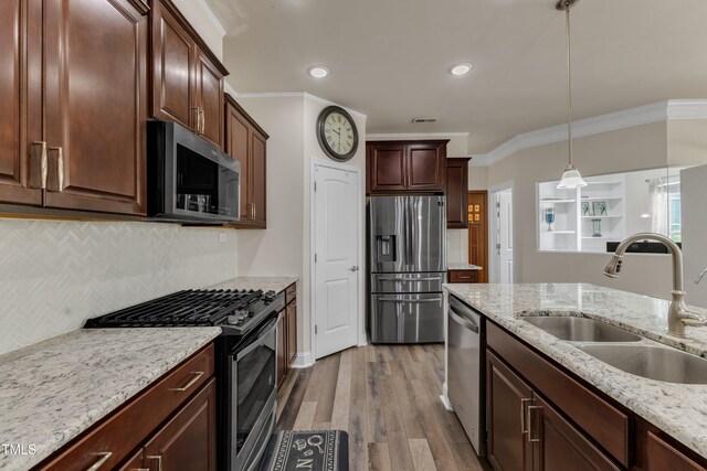 kitchen with stainless steel appliances, a sink, crown molding, backsplash, and light wood finished floors
