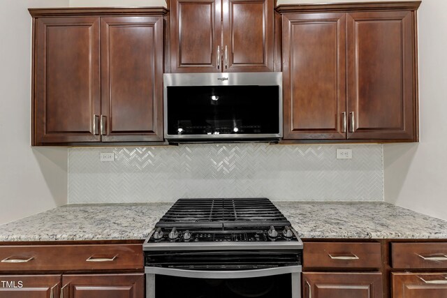 kitchen with stainless steel microwave, gas stove, dark brown cabinets, decorative backsplash, and light stone countertops