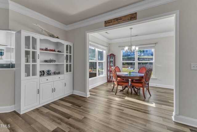 dining room with a chandelier, wood finished floors, ornamental molding, and baseboards
