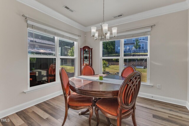 dining space with a chandelier, wood finished floors, crown molding, and baseboards