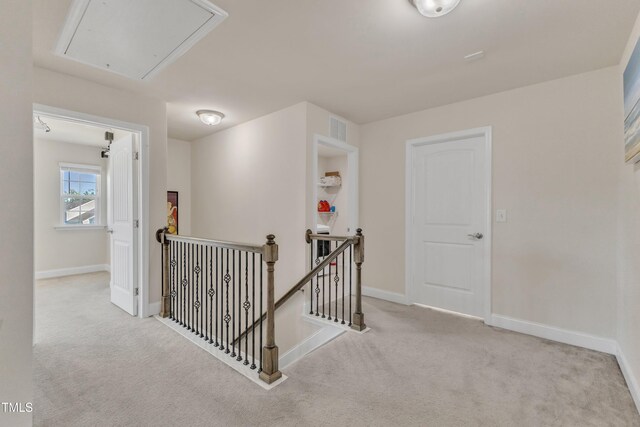 hallway featuring an upstairs landing, attic access, carpet flooring, and baseboards