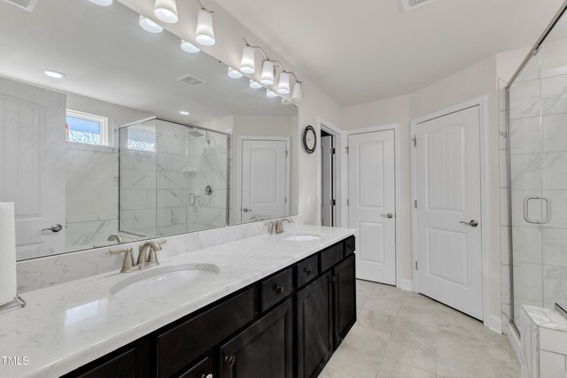 bathroom with a shower stall, double vanity, and tile patterned floors
