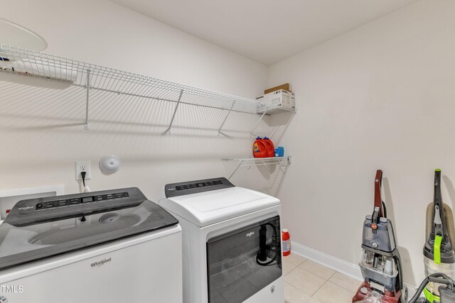 laundry area with washer and clothes dryer, light tile patterned floors, and baseboards
