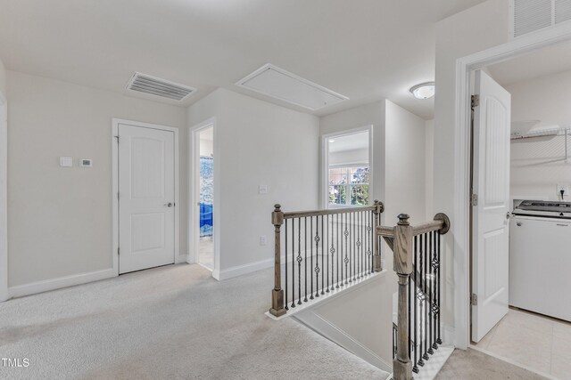 hallway with attic access, an upstairs landing, baseboards, and carpet floors