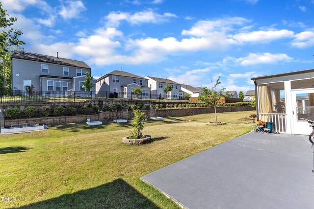view of yard featuring a residential view, a patio area, and a sunroom