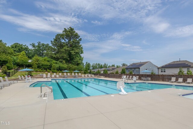 community pool with fence and a patio area