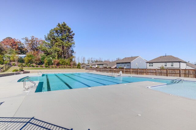 view of pool featuring fence, a patio area, and a residential view