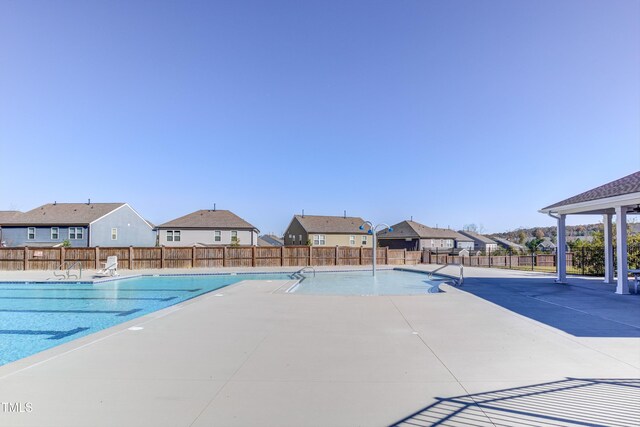 community pool featuring a residential view, fence, and a patio