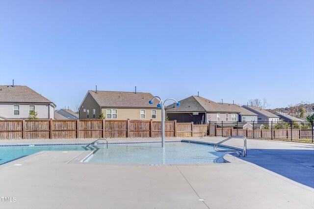 community pool featuring a residential view, a fenced backyard, and a patio area