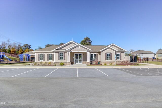 view of building exterior with uncovered parking and fence