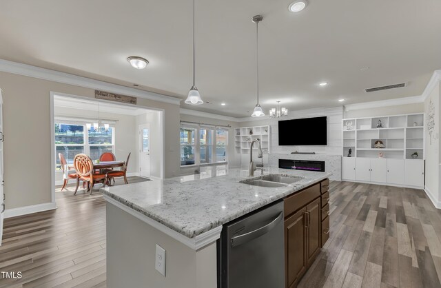 kitchen featuring a sink, a chandelier, stainless steel dishwasher, open floor plan, and ornamental molding