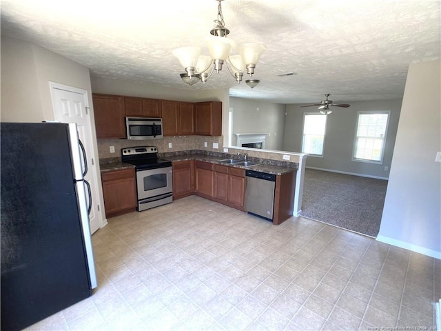 kitchen with stainless steel appliances, a sink, a textured ceiling, brown cabinets, and a ceiling fan