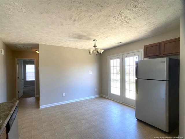 unfurnished dining area with plenty of natural light, a chandelier, a textured ceiling, baseboards, and light floors