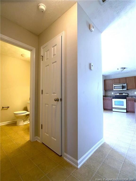 corridor featuring baseboards and light tile patterned flooring