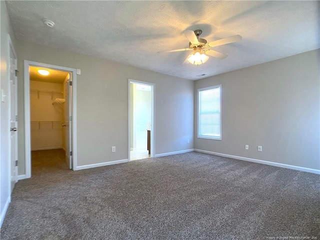 unfurnished bedroom with carpet, baseboards, a spacious closet, and a textured ceiling