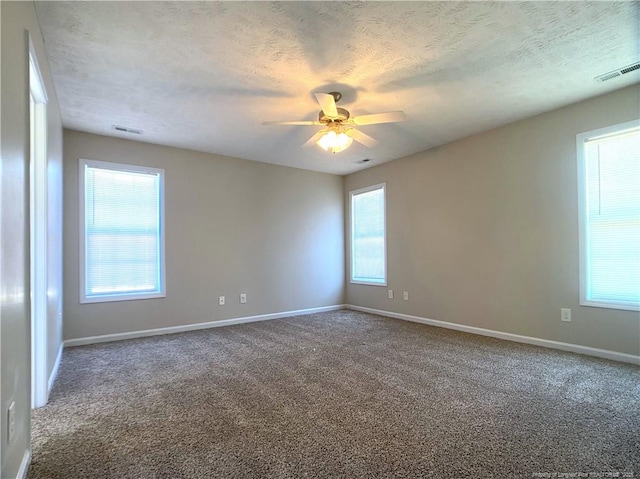 carpeted spare room with baseboards, ceiling fan, and a textured ceiling
