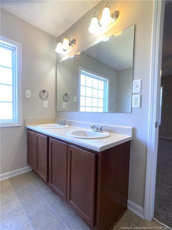 bathroom with double vanity, baseboards, and tile patterned floors