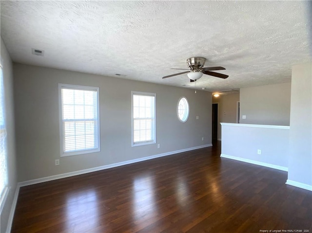 spare room featuring dark wood-type flooring, ceiling fan, a textured ceiling, and baseboards