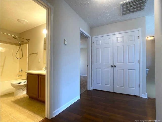 corridor featuring baseboards, wood finished floors, a textured ceiling, and a sink