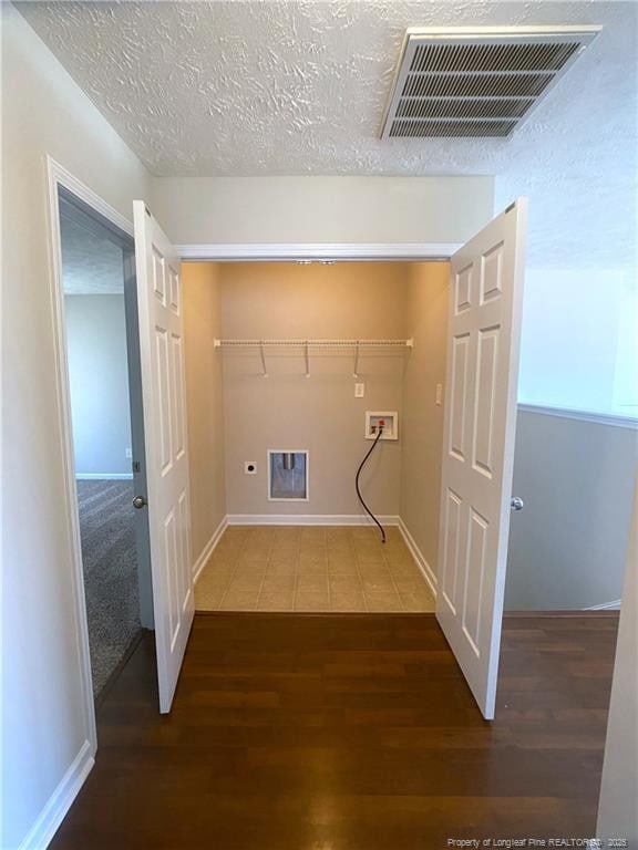 clothes washing area featuring hookup for a washing machine, wood finished floors, baseboards, and a textured ceiling