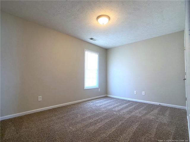empty room featuring a textured ceiling, baseboards, and carpet