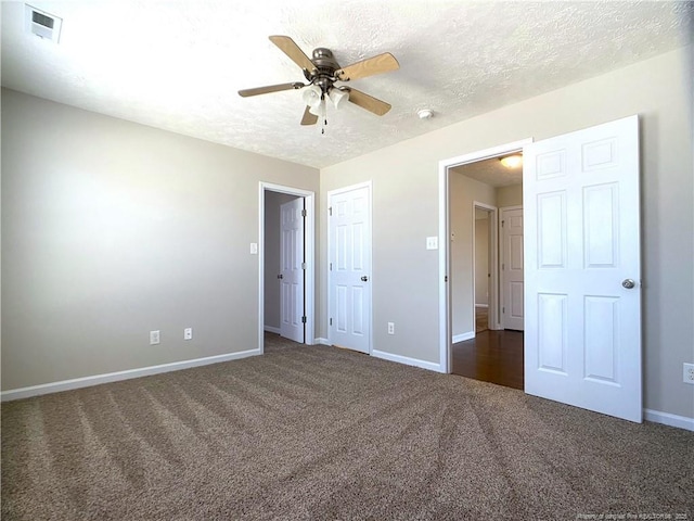 unfurnished bedroom with dark carpet, baseboards, a textured ceiling, and a ceiling fan