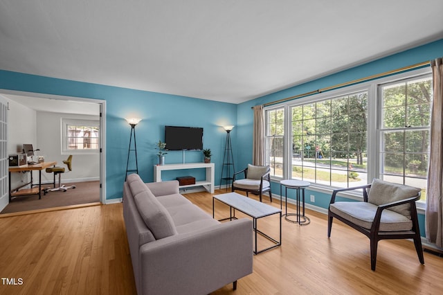 living room featuring healthy amount of natural light, an office area, light wood-style floors, and baseboards