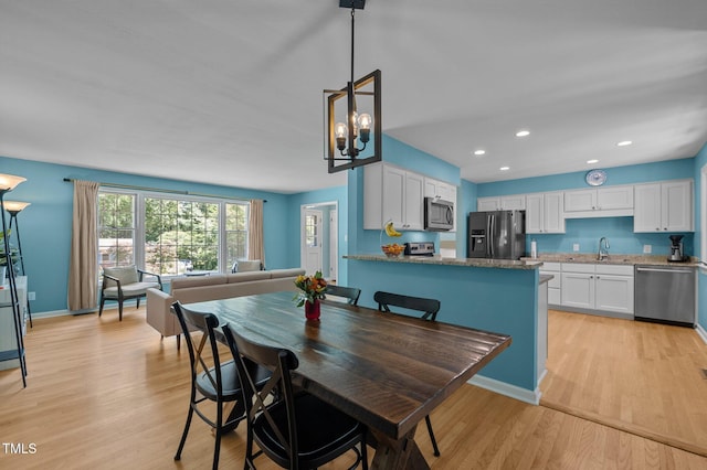 dining room with light wood finished floors, a chandelier, recessed lighting, and baseboards