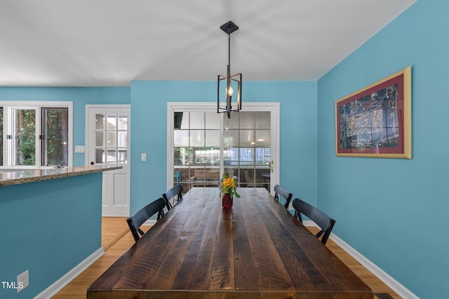 dining room with wood finished floors, healthy amount of natural light, baseboards, and a chandelier