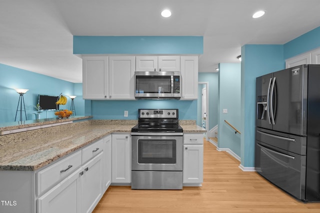 kitchen featuring appliances with stainless steel finishes, white cabinetry, light wood-type flooring, light stone countertops, and recessed lighting
