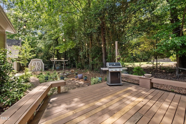 wooden deck with grilling area, a storage shed, and an outdoor structure