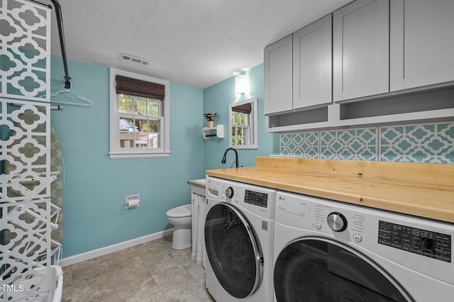 washroom with washing machine and dryer, baseboards, and light stone finish floors