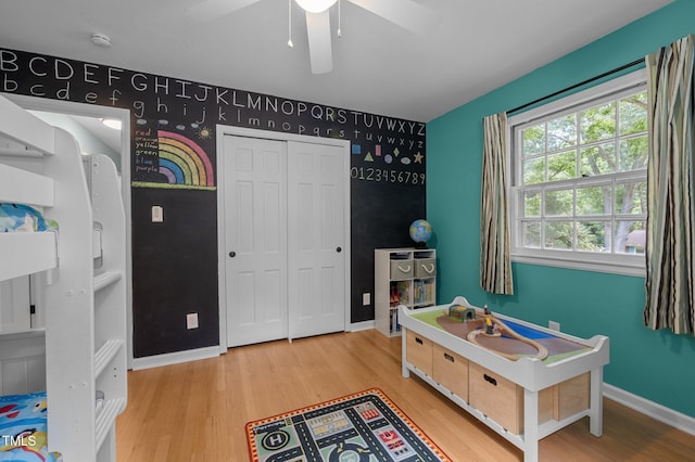 bedroom with wood finished floors, baseboards, an accent wall, and a closet