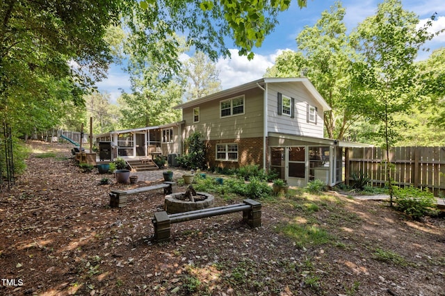 back of house with a sunroom, fence, and brick siding