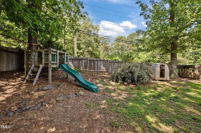 view of playground featuring a fenced backyard, a storage unit, and an outdoor structure