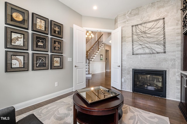 living area with stairway, wood finished floors, a tile fireplace, baseboards, and recessed lighting