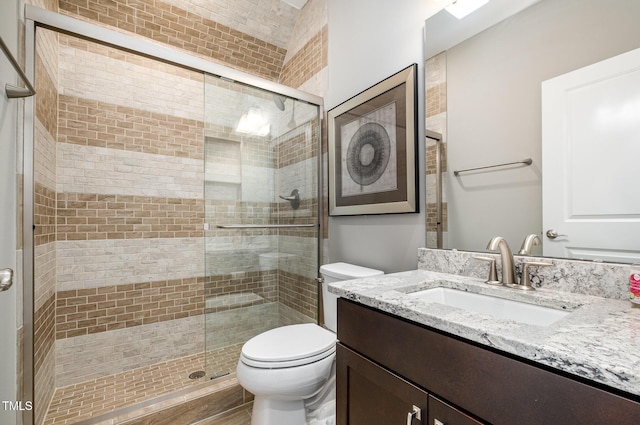 bathroom with a stall shower, toilet, and vanity